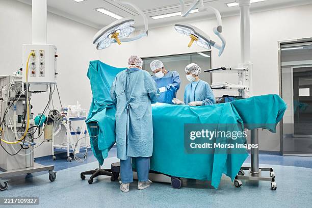 surgeons performing surgery in operating room - sala de cirurgia com assistência imagens e fotografias de stock