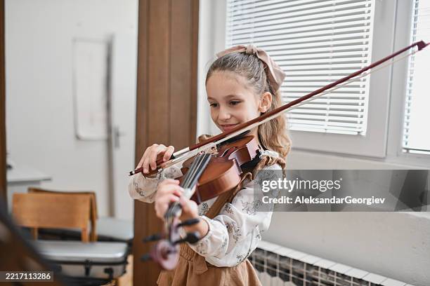 young musician appearing joyful and at ease while playing violin with full focus - violin stock pictures, royalty-free photos & images