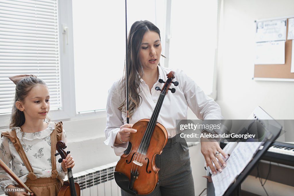 Female Professor Preparing Sheet Music for Young Student Violinist