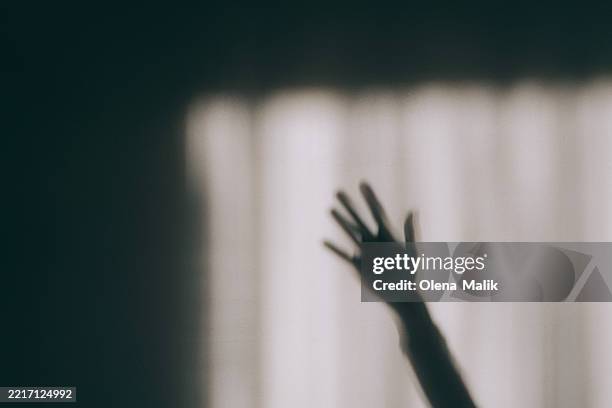 shadow of a hand on a textured wall surface - agresión fotografías e imágenes de stock