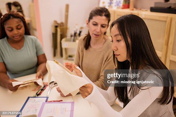 embroidery mentor supporting students in craft clas - cross stitch stock pictures, royalty-free photos & images
