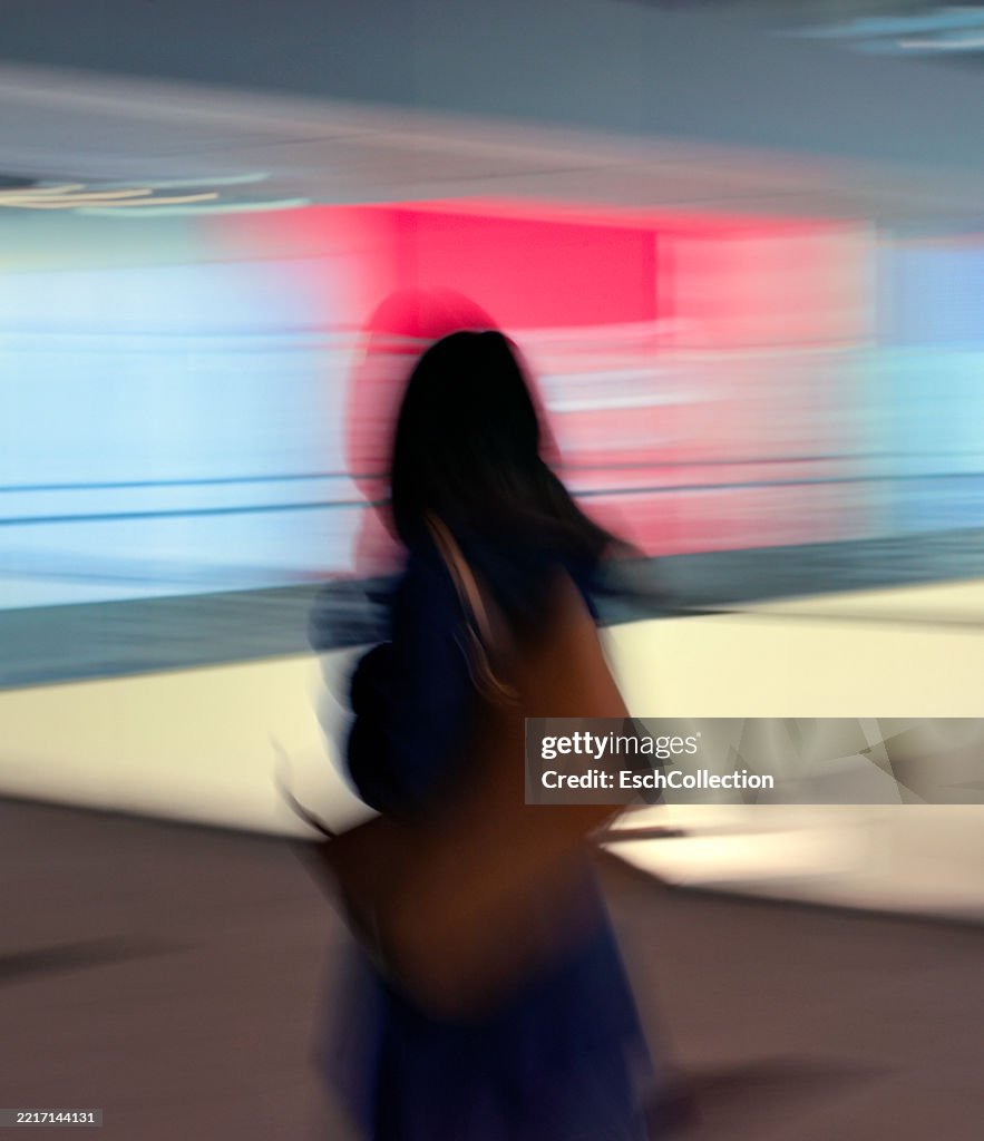 Young woman passing colorfully illuminated shop facades in Tokyo, Japan