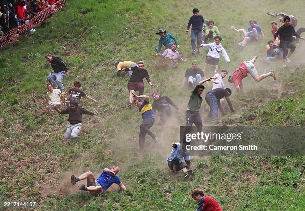 Contestants in the men's downhill race chase the cheese down the hill during Gloucestershire's famous Cheese-Rolling contest on May 26, 2025 in...