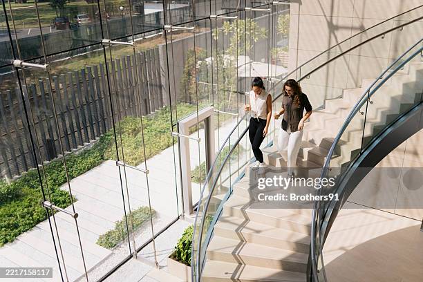 businesswomen walking and talking on modern office stairs - trap stockfoto's en -beelden