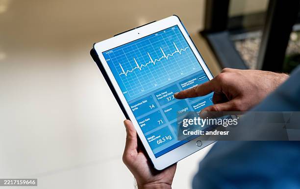 doctor monitoring the vital signs of a patient using a digital tablet - hartmonitor stockfoto's en -beelden