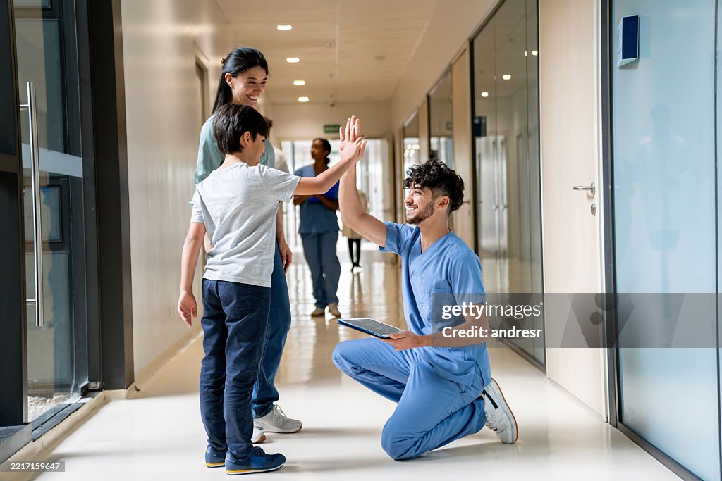 Glückliche Krankenschwester gibt einem Kind auf dem Flur eines Krankenhauses ein High-Five