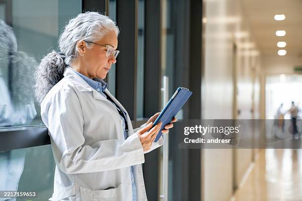 médico leyendo una historia clínica en una tableta digital en el hospital - resultado de pruebas médicas fotografías e imágenes de stock