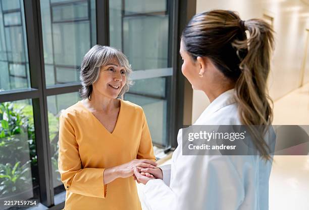 senior woman thanking her doctor while holding her hand at the hospital - sayings stock pictures, royalty-free photos & images