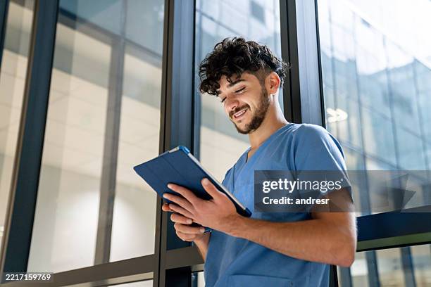 happy nurse using a digital tablet at the hospital and smiling - male medical student stock pictures, royalty-free photos & images