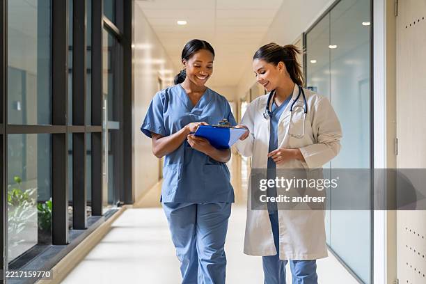 infirmière à l’hôpital montrant les résultats des tests à un médecin et souriant - suivi des malades photos et images de collection