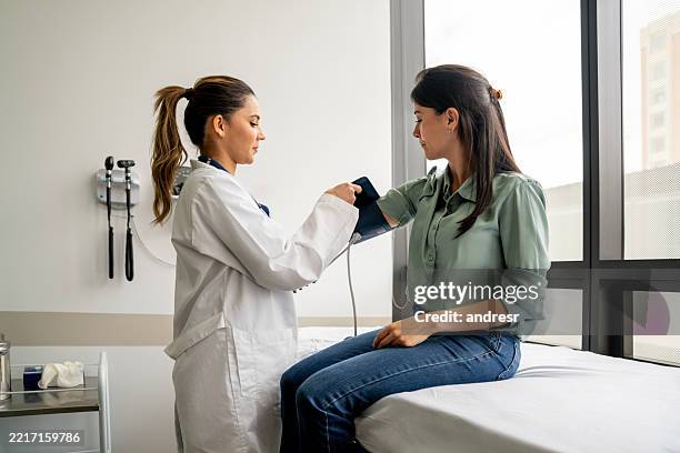 doctor checking the blood pressure on a woman in a consultation - exame médico imagens e fotografias de stock