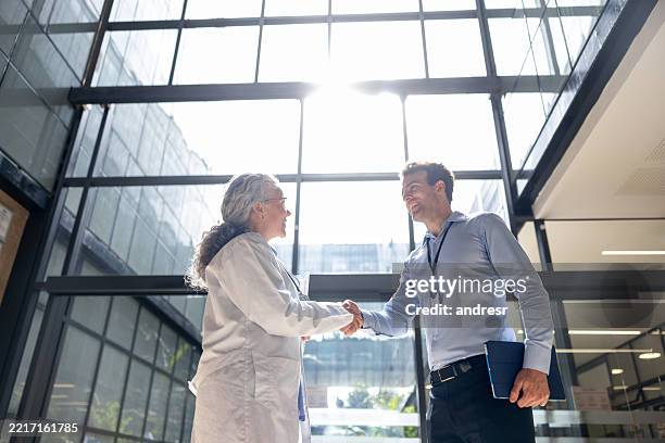 medical sales representative greeting a doctor with a handshake at the hospital - partnership stockfoto's en -beelden