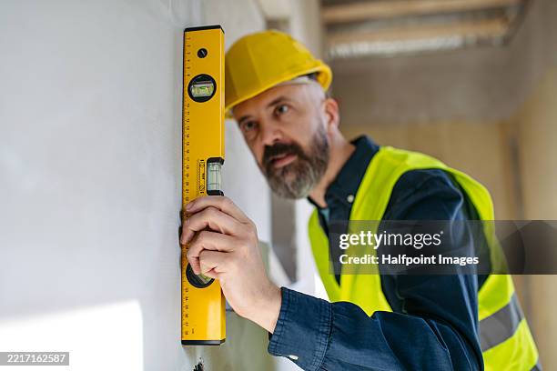 builder checking wall alignment using bubble level - waterpas stockfoto's en -beelden