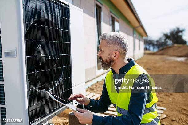 technician inspecting outdoor heat pump unit during home installation - home heating stock pictures, royalty-free photos & images