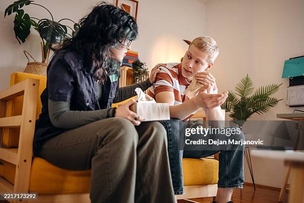 young couple having relationship difficulties and breaking up at home and crying - tissue stockfoto's en -beelden