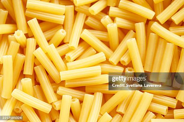 close-up view of uncooked tube-shaped pasta in a full frame composition - macaroni stock pictures, royalty-free photos & images