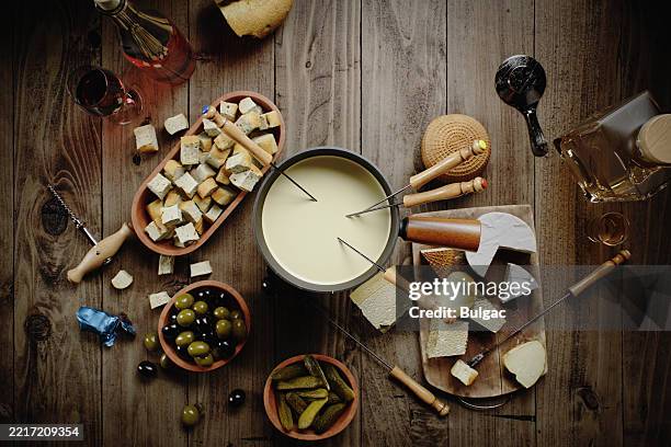 cheese fondue with bread, cheese, and wine on a rustic wooden table - cheese sauce stock pictures, royalty-free photos & images
