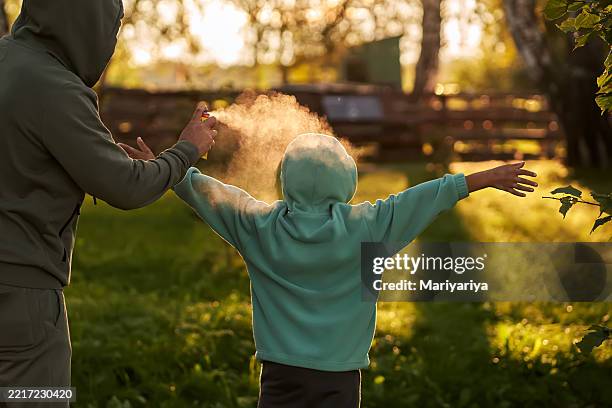 a man sprays a child with insect repellent in a forest. - tick bite stock pictures, royalty-free photos & images