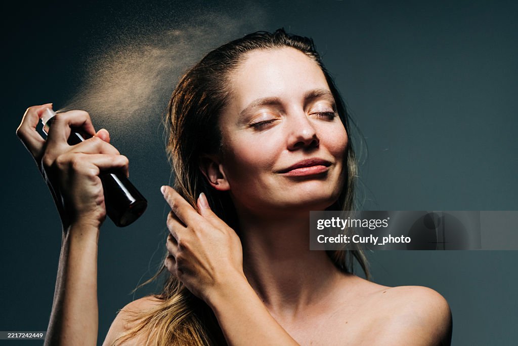 Woman haircare concept. Woman spraying hairspray.