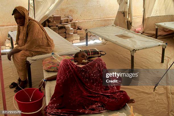 Woman sits next to her child suffering from cholera at an isolation unit outside the Bashayer Hospital, south of Khartoum on May 31, 2025. In...