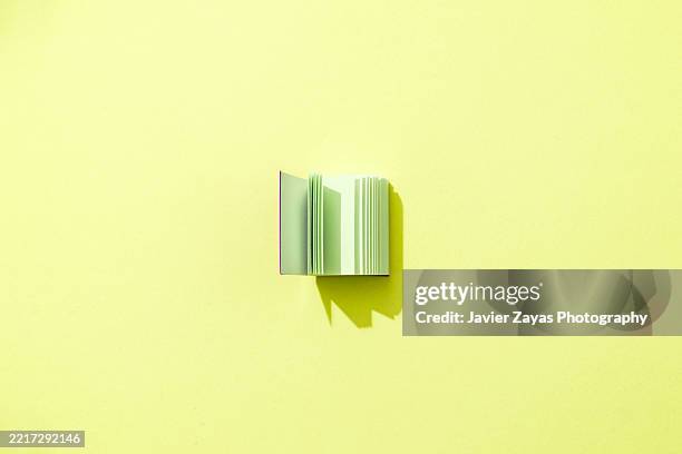 book open on a yellow background casting a shadow - blank pages in open book overhead view stock pictures, royalty-free photos & images