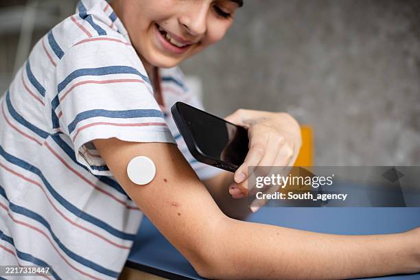 junger junge, der typ-1-diabetes mit technologie zu hause behandelt, während er den blutzucker testet - blutzuckerspiegel stock-fotos und bilder