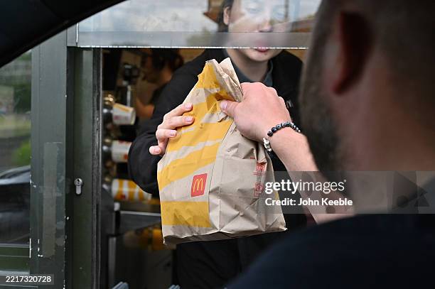 Driver collects a McDonald's order at a drive-through restaurant on May 25, 2025 in Basildon, United Kingdom.