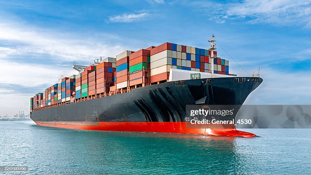 Container tanker ship carrying truck size colourful containers in deep blue sea.