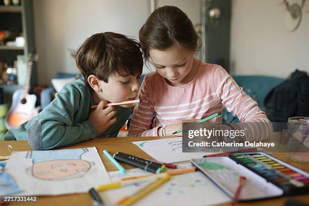 a brother and his sister doing crafts at home - mittleres kindesalter stock-fotos und bilder