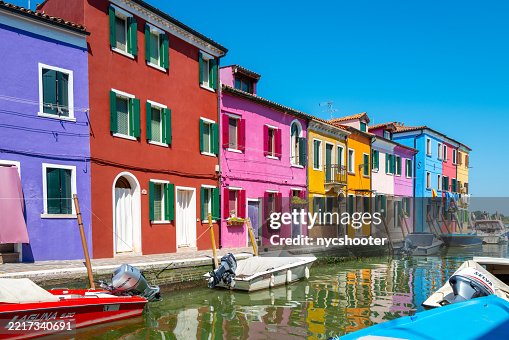 Burano, a colorful island in Venice, showcases charming houses painted in vibrant hues. The sun shines brightly on the canal, creating a perfect summer getaway spot filled with unique architecture Burano, a colorful island in Venice, showcases charming houses painted in vibrant hues. The sun shines brightly on the canal, creating a perfect summer getaway spot filled with unique architecture