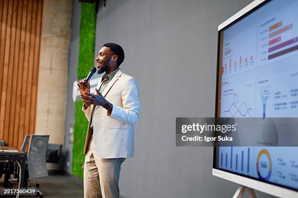 motivational speaker presenting sales data analysis using a microphone and interactive whiteboard - education event stock pictures, royalty-free photos & images