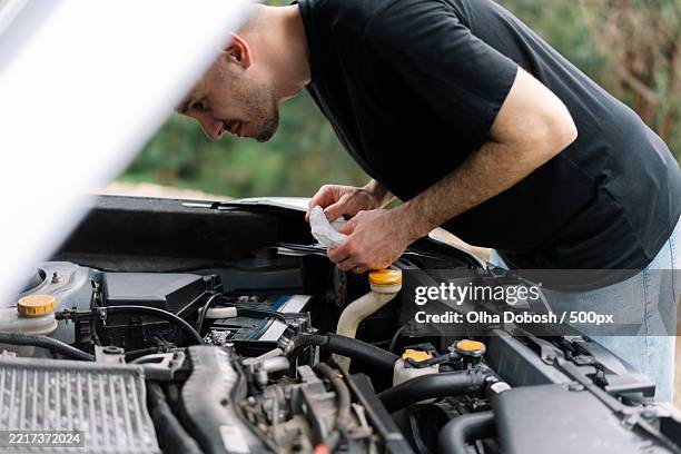 side view of man repairing car - oil check car stock pictures, royalty-free photos & images