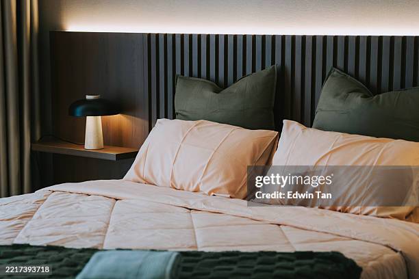 modern cozy bedroom with warm lighting and earth-tone bedding - bedclothes stock pictures, royalty-free photos & images