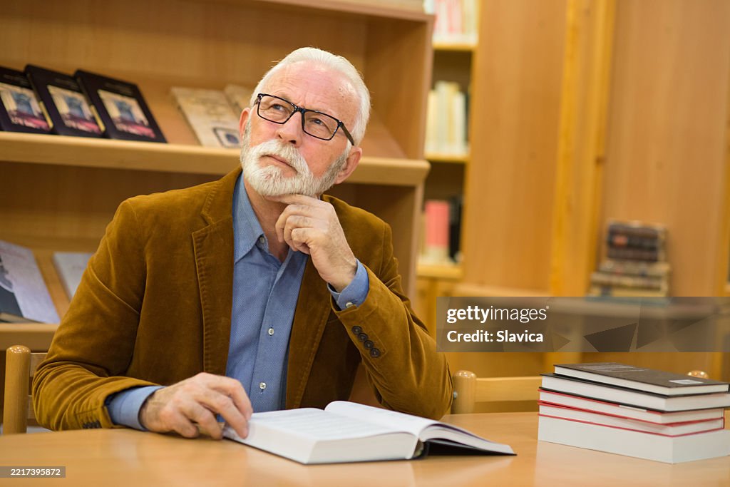 Senior man reading books in the library