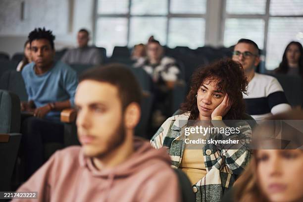 bored black college student attending a class in amphitheater. - boredom stock pictures, royalty-free photos & images