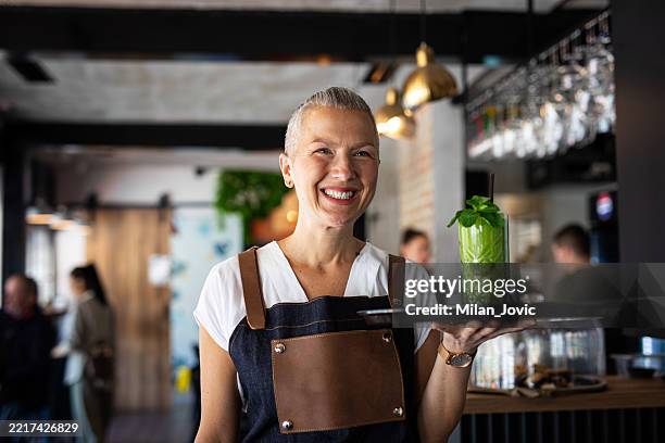 smiling waitress serving fresh green cocktail in modern café - bandeja de serviço imagens e fotografias de stock