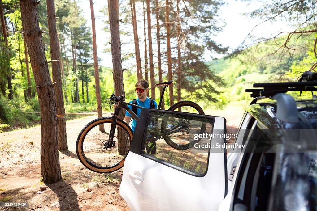Young man preparing for mountain biking in a forested outdoor area