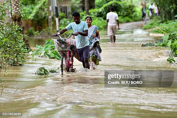 Man pushes his bicycle through a flooded street after heavy rains in Kampur at Nagaon district, in India's northeastern state of Assam on June 1,...