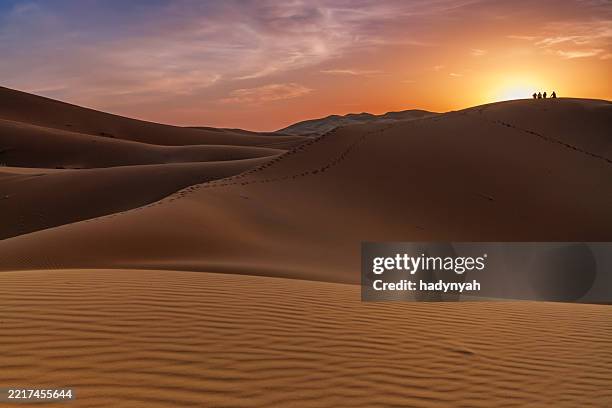 tourists watching the sunrise over sand dunes, morocco - desierto del sáhara del oeste fotografías e imágenes de stock