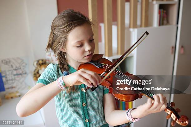 a 9 year old girl playing violin in her bedroom - außerschulische aktivität stock-fotos und bilder