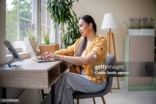 monitoring health at home with technology in a bright and modern living space - type 1 diabetes stock pictures, royalty-free photos & images