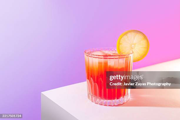 refreshing cranberry juice with ice cubes and lemon slice on vibrant gradient background - lemon slice isolated stock pictures, royalty-free photos & images