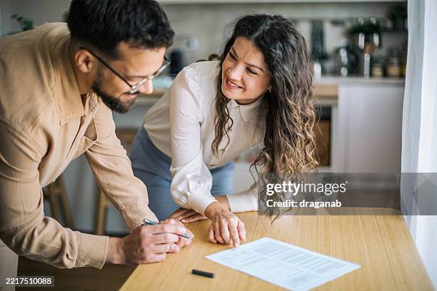 couple reading and signing contract at home - tenant stock pictures, royalty-free photos & images