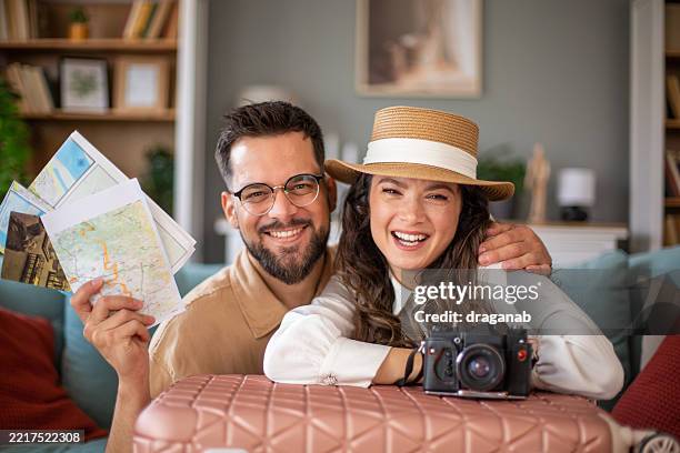 young couple smiling and planning their next trip with maps and camera - honeymoon stock pictures, royalty-free photos & images