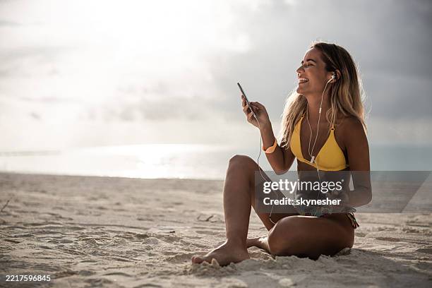 happy woman listening music over cell phone on the beach. - mp3 player stock pictures, royalty-free photos & images