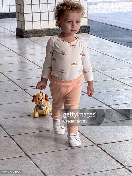 achtzehn monate altes mädchen lockiges blondes haar lebensstil - mit mobilgerät aufgenommen stock-fotos und bilder