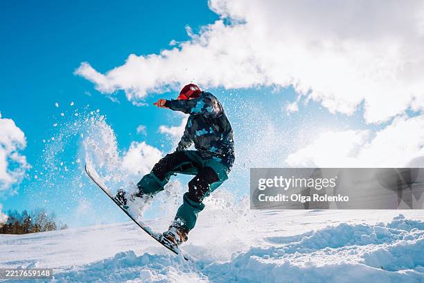 snowboarder performing a jump on a sunny day - snowboard stockfoto's en -beelden
