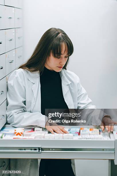 young pharmacist searching medicine in pharmacy drawer - images for hospital management system stock pictures, royalty-free photos & images