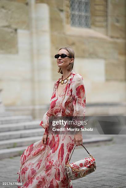 Marlies Pia Pfeifhofer is seen wearing a light beige silk chiffon long sleeve maxi dress with red and pink prints of feathers and flowers, drawstring...