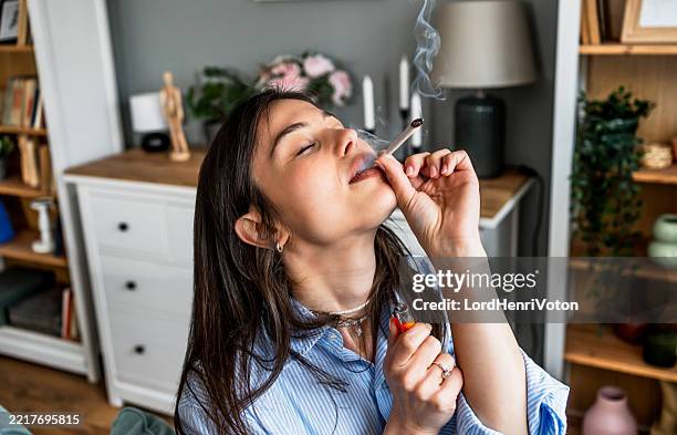 young woman smoking marijuana joint at home - legalization stock pictures, royalty-free photos & images